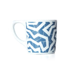 White coffee mug with a blue printed zig zag pattern.