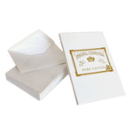 On top of a stack of white envelopes sits an envelope with its flap opened.  Leaning against the envelopes is a white writing pad with an Original Crown Mill branded gold seal which features a crown and an Old English font.