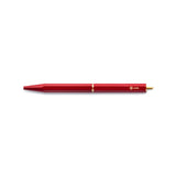 The Red Brassing Portable Ball Point Pen has flat sides for grip, a brass-colored scalloped center seam, a small, brass-colored, ystudio logo, and a narrow, brass end.