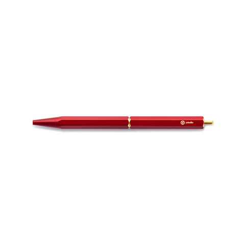 The Red Brassing Portable Ball Point Pen has flat sides for grip, a brass-colored scalloped center seam, a small, brass-colored, ystudio logo, and a narrow, brass end.